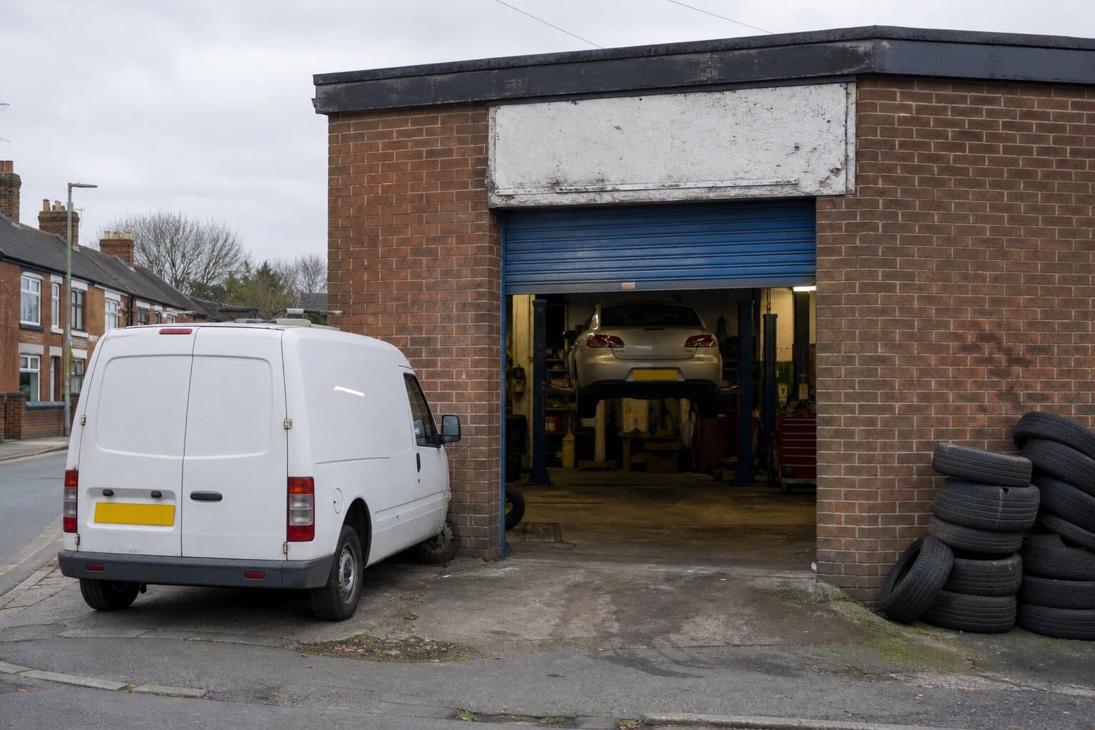 A small independent car repair garage with an open bay and a van on the forecourt.